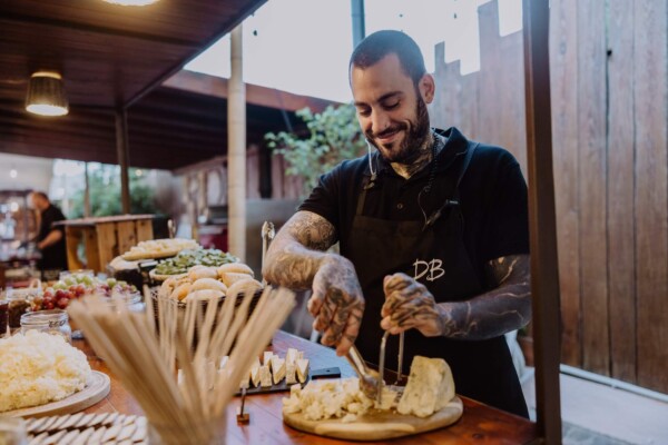 Cocinero profesional sirviendo buffet de quesos artesanos en el aperitivo de una boda en la playa DBlanc.