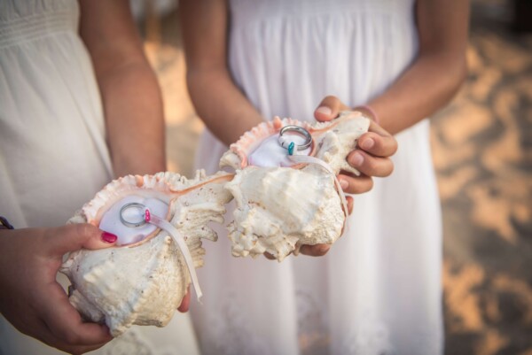 Detalle de anillos de boda sujetos con lazos dentro de grandes caracolas de mar naturales en DBlanc.
